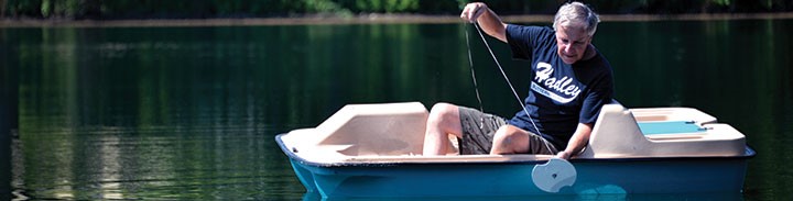 Man in a paddleboat pulling a water-monitoring device out of the water