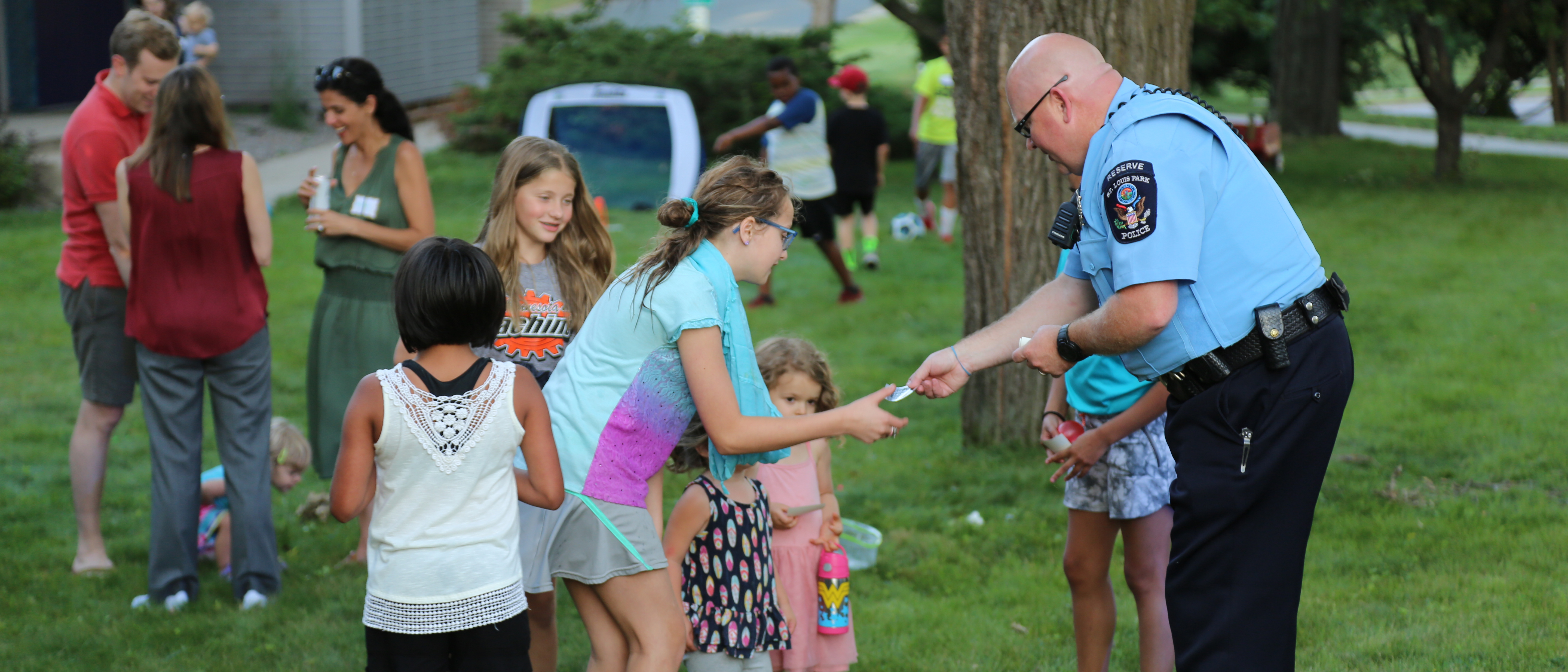 Police reserve volunteer handing out stickers to kids